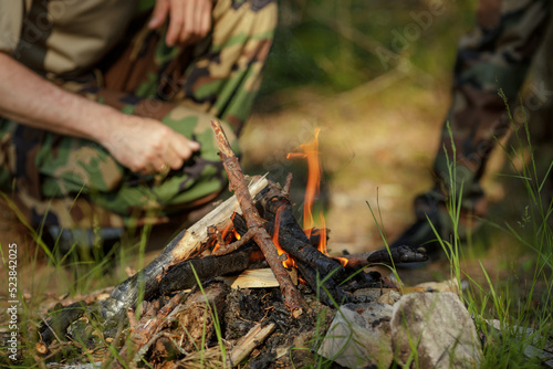 Man is making campfire in the woods. The concept of adventure, travel, tourism, camping, survival and evacuation.