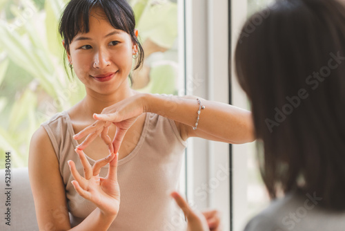 Young attractive Asian women using sign hand finger language conversation with deaf person. Cheerful happy using nonverbal communication to persons with disabilities.