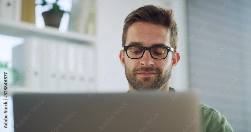 Small business owner or startup entrepreneur working on his laptop, remote from home in his office or study. Business man wearing glasses typing and sending email communication while smiling
