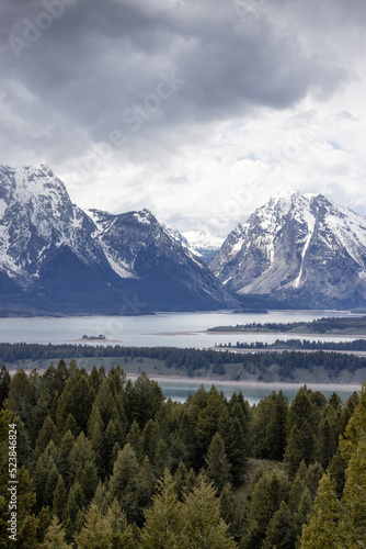 Lake surrounded by Trees and Mountains in American Landscape. Spring Season. Jackson Lake, Grand Teton National Park. Wyoming, United States. Nature Background.