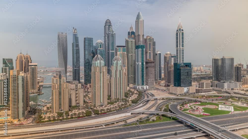 Skyscrapers of Dubai Marina with illuminated highest residential buildings morning timelapse. Traffic on highway intersection. Aerial top view from JLT district during sunrise Skyscrapers of Dubai Marina with illuminated highest residential buildings morning timelapse. Traffic on highway intersection. Aerial top view from JLT district during sunrise