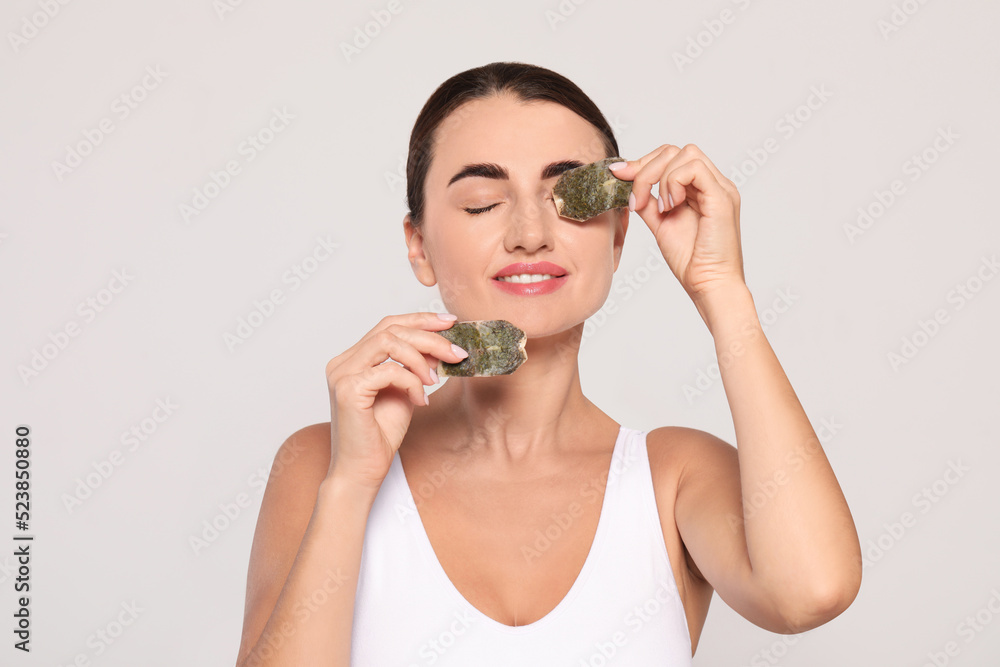 Beautiful woman applying green tea bags on skin under eyes against