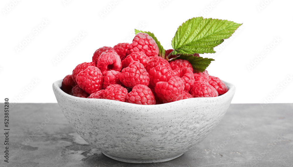 Bowl of fresh ripe raspberries with green leaves on grey table against white background Bowl of fresh ripe raspberries with green leaves on grey table against white background