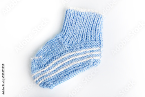 Knitted baby socks in blue color on a white background. The concept of warm things from a woolen thread