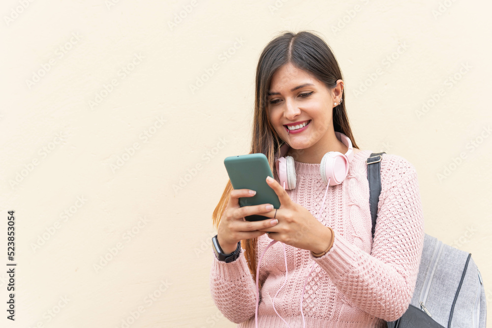 girl smiling typing on the cell phone on yellow background girl smiling typing on the cell phone on yellow background