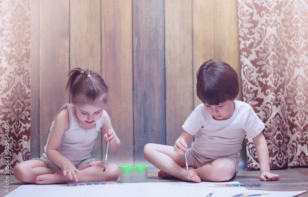 Little children paint on a large sheet of paper Little children paint on a large sheet of paper