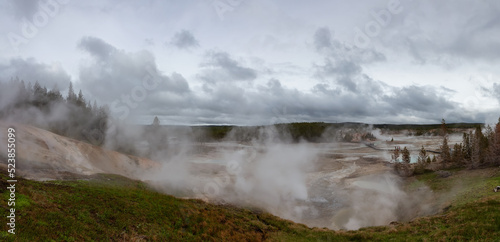 Hot spring Geyser with colorful water in American Landscape. Cloudy Sky. Yellowstone National Park, Wyoming, United States. Nature Background Panorama