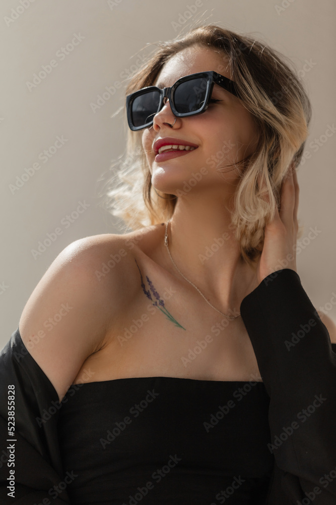 Happy Fashionable Women's Urban Portrait of a beautiful woman model with a smile and cool modern sunglasses in fashion black business clothes with a blazer and top in the city Happy Fashionable Women's Urban Portrait of a beautiful woman model with a smile and cool modern sunglasses in fashion black business clothes with a blazer and top in the city
