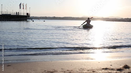 the silhouette of a canoeist while canoeing at sunset photo