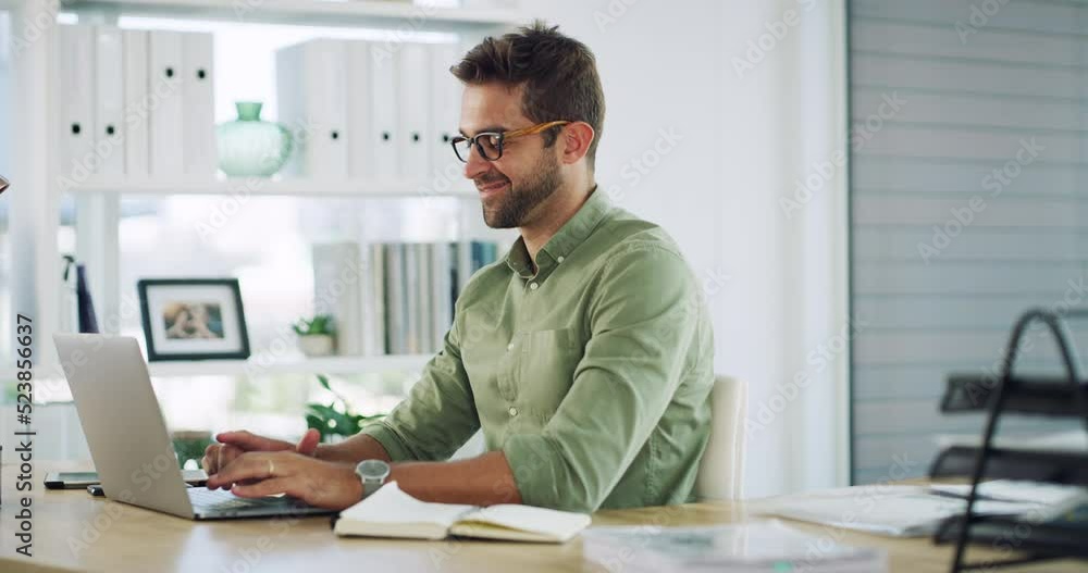 Handsome, smiling and happy businessman sitting alone working in his office on a laptop. Man thinking while typing emails with a vision for employee growth, plan or strategy for online startup.