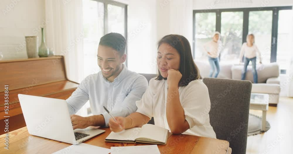 Home budget, finance planning and money management with a happy couple in the dining room and kids in the background. Family investment and savings for the future and their carefree children Home budget, finance planning and money management with a happy couple in the dining room and kids in the background. Family investment and savings for the future and their carefree children