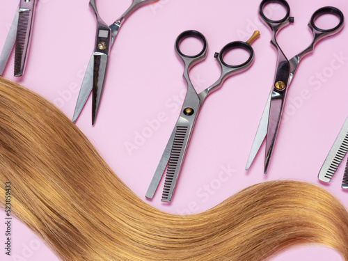 Set of professional hairdressing scissors. Long blond hair on pink. The concept of healthy hair, care for blondes