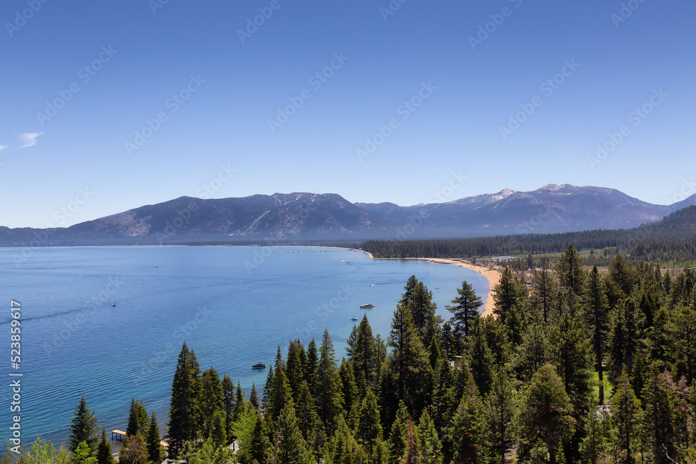 Large Lake with Beach surrounded by Trees and Mountains. Summer Season. Lake Tahoe, California, United States. Nature Background.