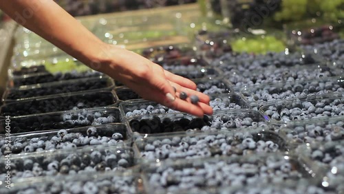 Woman's hands choose blueberries in a supermarket close-up