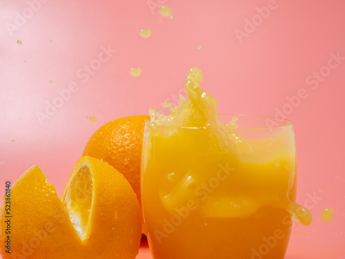 Orange and orange slice. Orange Juice Splashing. Orange on a pink background.
