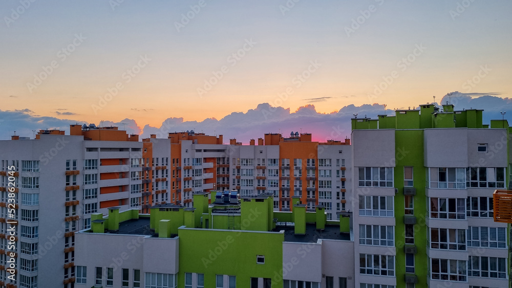 modern colorful apartment residential buildings skyscrapers in the city, sunset sunrise time, orange clouds, big city life 