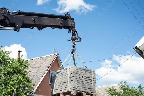 Unloading paving slabs from a truck. Men unload paving slabs using a manipulator. Workers unload building materials from a large machine.