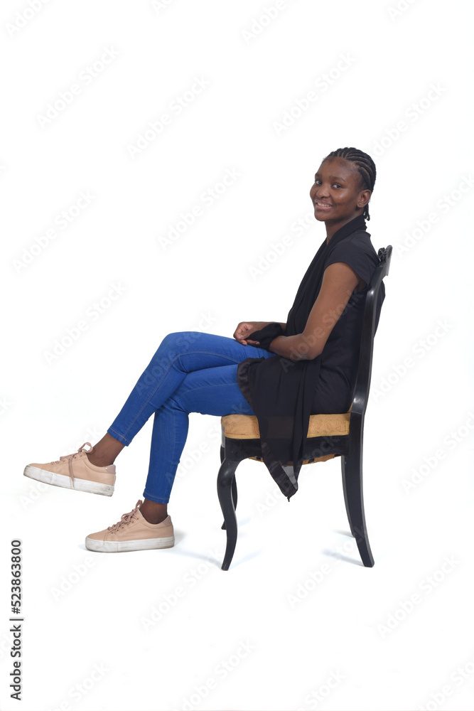 side view of a full portrait of a woman sitting on chair cross-legged an looking at camera over white background side view of a full portrait of a woman sitting on chair cross-legged an looking at camera over white background
