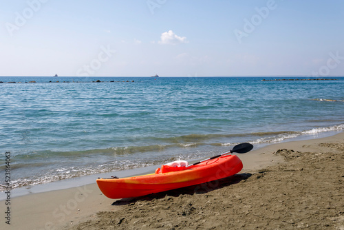 Orange kayak boat on empty sandy sea beach on sunny summer day
