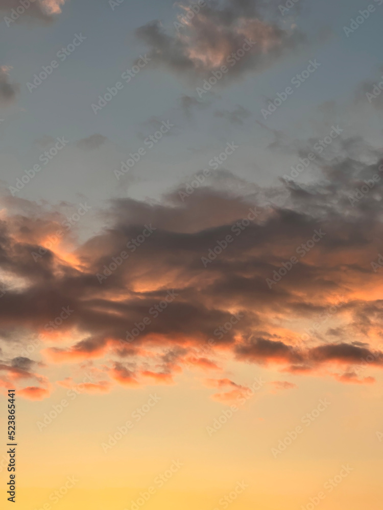 Dramatic sunset landscape with puffy clouds lit by orange setting sun and blue sky. Dramatic sunset landscape with puffy clouds lit by orange setting sun and blue sky.