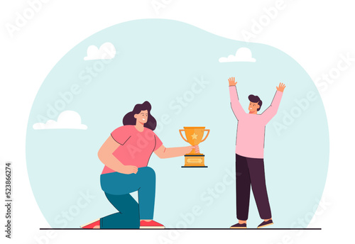 Woman rewarding gold goblet to kid flat vector illustration. Happy little boy winning first place prize. Victory, leadership, competition concept for banner, website design or landing web page