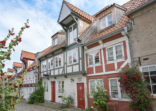 Historic half-timbered houses in the old town of Flensburg, Germany, on a narrow cobblestone alley with flowers on the facades, tourist attraction, selected focus © Maren Winter