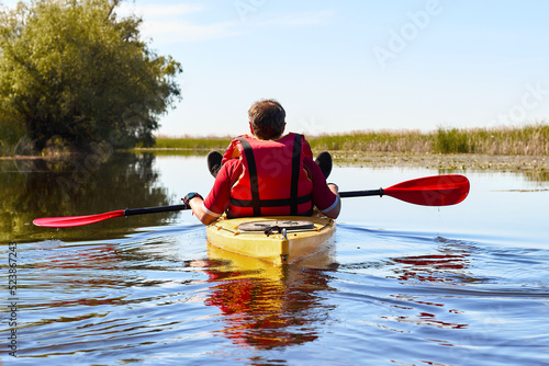 Man sits on yellow kayak on the river at summer season