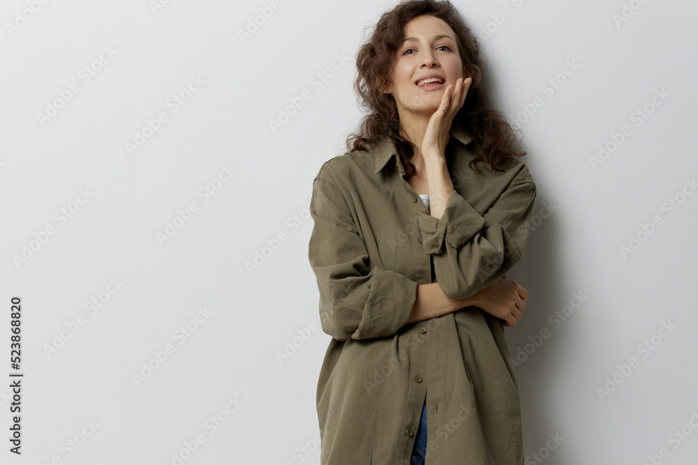 Smiling happy curly beautiful woman in casual khaki green shirt recline on hand looks at camera enjoy cool day posing isolated on over white background. People Emotions Lifestyle concept. Copy space Smiling happy curly beautiful woman in casual khaki green shirt recline on hand looks at camera enjoy cool day posing isolated on over white background. People Emotions Lifestyle concept. Copy space