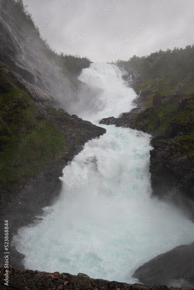 The powerful Kjosfossen waterfall roars while his water drops more than 200m down from the cliffs, Myrdal, Norway