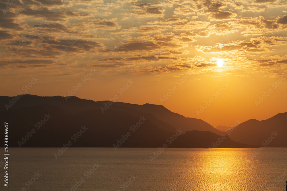 Marmaris, Turkey – Beautiful sunset in  the silent coast of small cozy resort town with its misty yellow mountains at background and the gold bay.