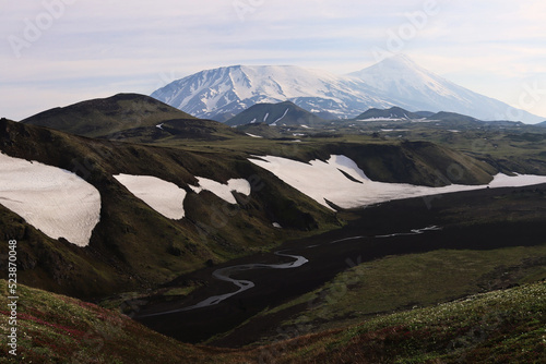 Kamchatka. A journey through the wilderness. A mountain river flows between snow-capped volcanoes. Flat Tolbachik. Hiking in the mountains
