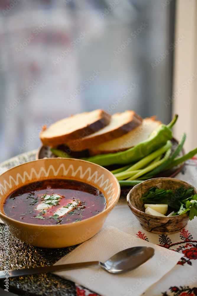 Traditional Ukrainian borscht with sour cream in a clay bowl.