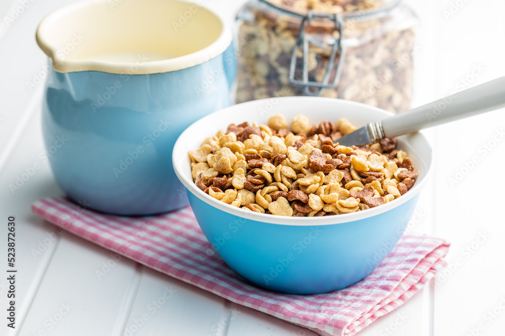 Breakfast cereal flakes in bowl and milk on checkered napkin. Breakfast cereal flakes in bowl and milk on checkered napkin.