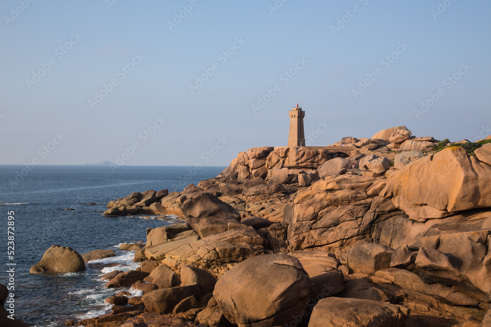 The lighthouse Men Ruz with bridge towering the extraordinarily colored and fantastically shaped rock formations at the atlantic ocean-the famous pink granite coast, Brittany, France