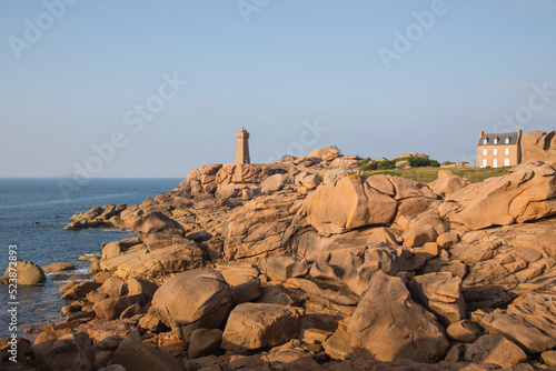 Lighthouse Men Ruz and museum Maison Littoral towering the extraordinarily colored stones and fantastically shaped rock formations at the Atlantic Ocean-pink granite coast, Brittany, France photo