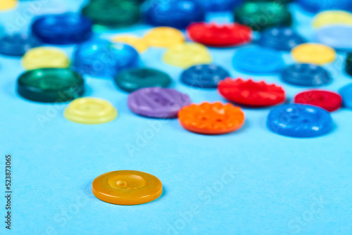 Multicolored buttons for clothess on a blue background. Close-up, selective focus