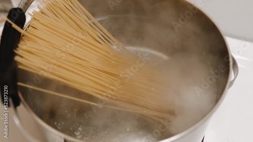 The cook throws pasta into boiling water. Cooks spaghetti for shrimp pasta.