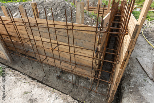 Tied rebar and mounted formwork close-up before pouring the strip foundation when building a house