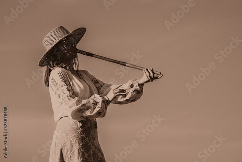 Woman plays on wooden flute - ukrainian telenka, tylynka. Retro toning. sepia. Folk music, sopilka concept. Musical instrument. Musician in traditional embroidered shirt - Vyshyvanka. photo