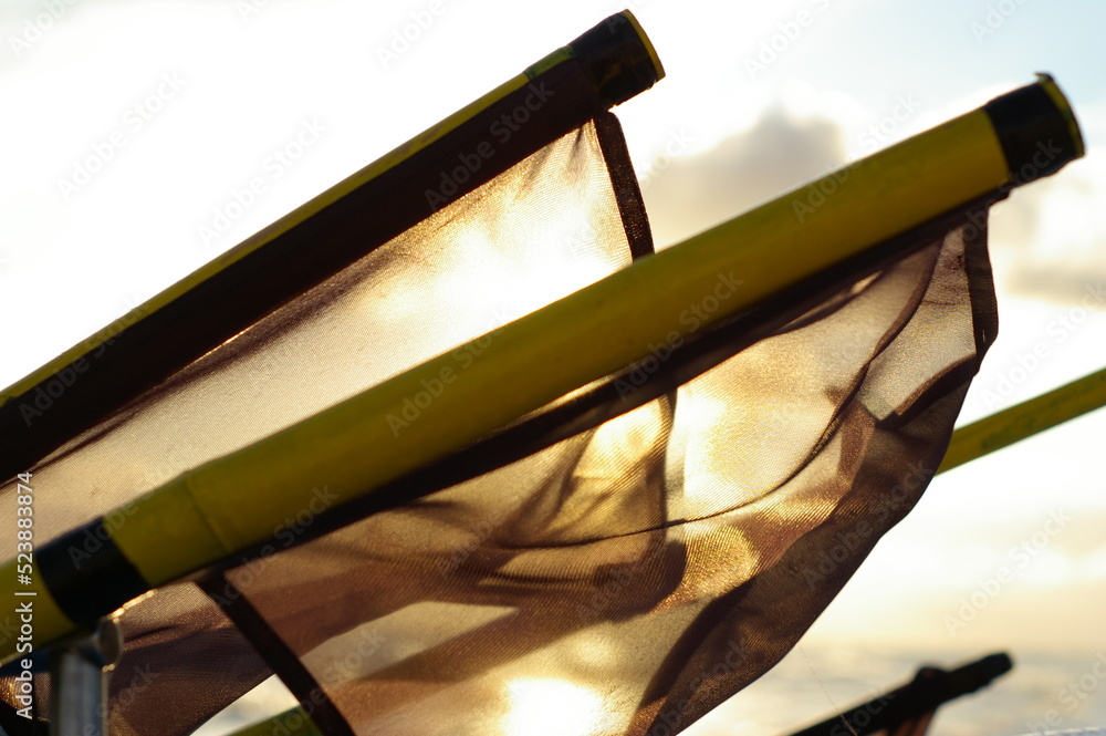 Czarne flagi rybackie na tle wschodzącego słońca - obrazy, fototapety, plakaty 