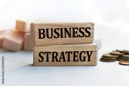 The inscription BUSINESS STRATEGY on wooden cubes isolated on a light background. Concept word forming on wooden cube. Business, economics and finance concept.