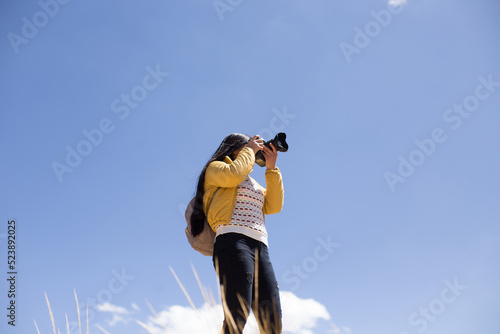 Mujer fotógrafa haciendo fotos con el cielo azul de fondo. Concepto de profesiones, turismo, viajes, aventura y personas. photo