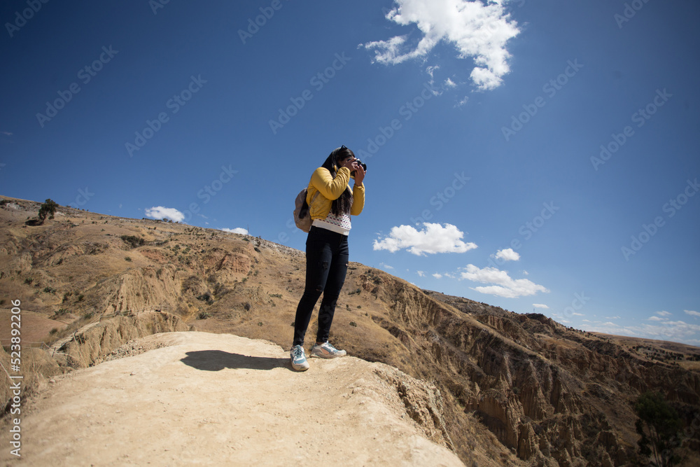 Mujer turista tomando fotos con una cámara profesional en una montaña turística de sudamérica. Concepto de tecnología, viajes, vacaciones y turismo. Mujer turista tomando fotos con una cámara profesional en una montaña turística de sudamérica. Concepto de tecnología, viajes, vacaciones y turismo.