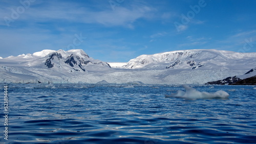Icebergs floating at the base of snow covered mountains in Cierva Cove, Antarctica