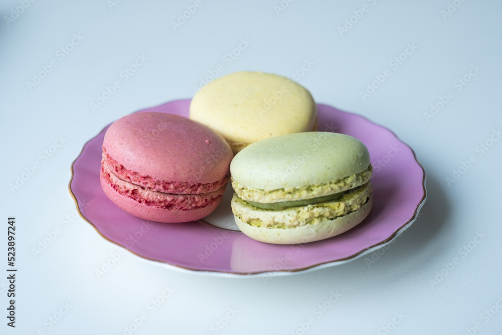 Mix of appetizing macarons in porcelain plate with blue background. Greeting card. Sweet concept. Excellent image for dessert banners and advertisements. Place for your text. Mix of appetizing macarons in porcelain plate with blue background. Greeting card. Sweet concept. Excellent image for dessert banners and advertisements. Place for your text.