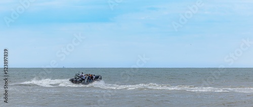 Speedboat with tourists sailing on the blue wavy sea photo
