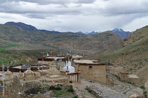 Houses in Tashigang village in Spiti valley, India surrounded by mountains covered with clouds photo