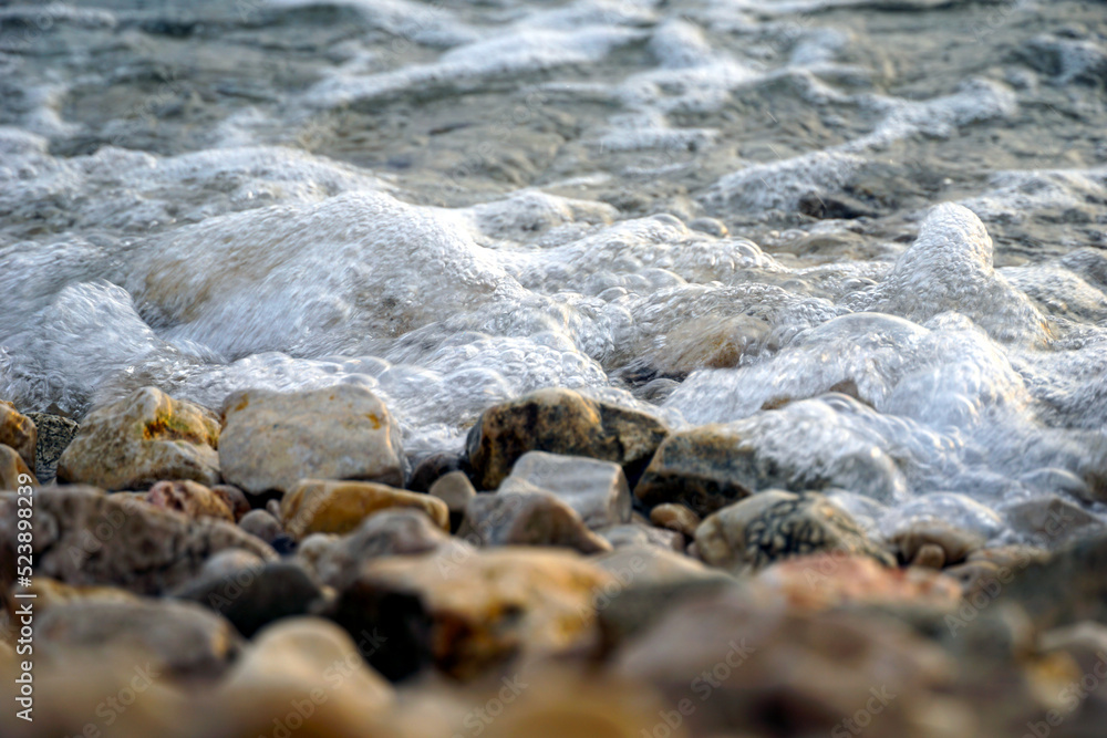 Sea foam covering a pebble beach in a shallow sea