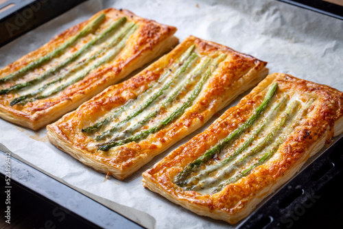 Baked green asparagus with ham and cheese in puff pastry sprinkled