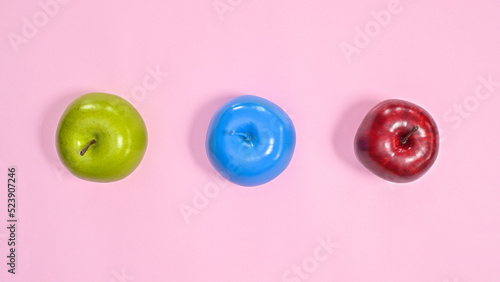 Green , red and blue apples on pastel pink background. Creative colorful healthy lifestyle concept. Flat lay minimal